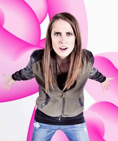 a woman with her arms outstretched in front of a pink and white background that looks like flowers