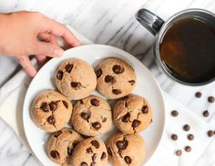 a white plate topped with chocolate chip cookies next to a cup of coffee