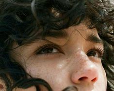 a close up of a person with freckles on their face and hair blowing in the wind