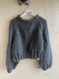 a gray sweater hanging on a white wall