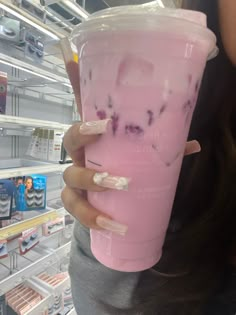 a woman holding up a pink drink in a store