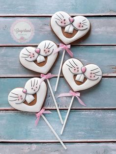 four decorated heart shaped lollipops sitting on top of a wooden table next to each other