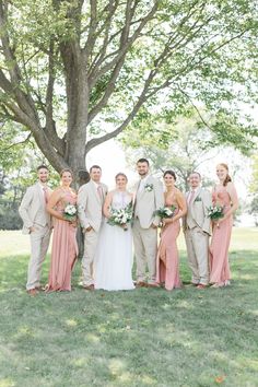 a bride and groom with their bridal party in front of a large oak tree