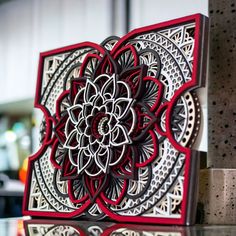 a red and white card with an intricate design on the front is sitting on a glass table