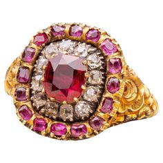 A superb antique Georgian ruby and diamond ring made in England, circa 1820. The centre of this ‘target’ shaped cluster ring is set with a 1ct cushion cut deep red ‘pigeon’s blood’ ruby, probably Burmese origin. Neatly prong-set, it is encircled by a halo of old cut diamonds in crimpled collet silver settings which is further surrounded halo of smaller cushion cut rubies. The ring is typical of early 19th century Georgian design with its intricate repoussé-work shoulders, decorated with roses an Georgian Rings Antique, Georgian Ring, Blood Ruby, Georgian Jewelry, Antique Jewelry Rings, Ruby And Diamond Ring, Ruby Diamond, Antique Jewellery, Antique Rings