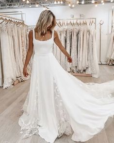 a woman standing in front of a rack of wedding dresses at a bridal shop