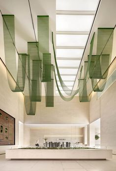 the interior of a modern building with green ribbons hanging from the ceiling