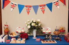 a blue table topped with cakes and desserts next to a flag banner on the wall