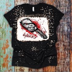 a black t - shirt with an image of a knife and blood splatters on it