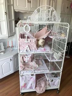 a white birdcage filled with lots of pink items in a room next to a dresser