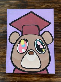 a painting of a teddy bear wearing a graduation cap on top of a wooden table