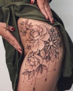 a woman is showing off her thigh with flowers on the side and tattoos on it