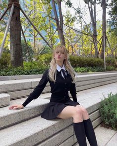 a woman sitting on steps in a skirt and jacket