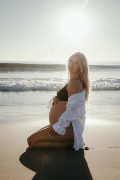 a pregnant woman is sitting on the beach