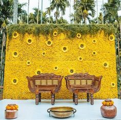 two wooden benches sitting next to each other on a white table with yellow flowers behind them