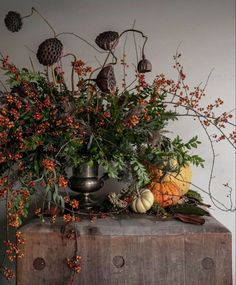 a vase filled with flowers sitting on top of a wooden table next to a wall