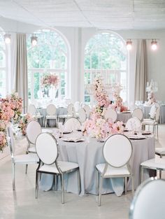 a room filled with lots of tables covered in white and pink flowers