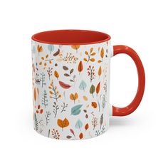 a red and white coffee mug with leaves on the inside is sitting in front of a white background