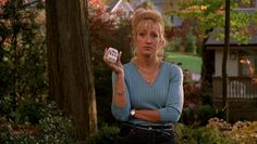 a woman standing in front of some trees holding a jar with something on top of it