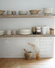 the shelves are filled with bowls and plates on them, along with other kitchen items