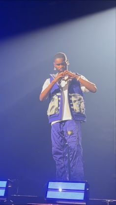 a man standing on top of a stage with his hands in his pockets and headphones to his ears