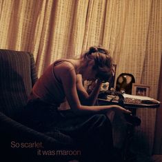 a woman sitting on top of a couch in front of a table with a clock