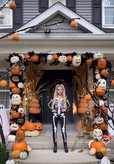 a woman in skeleton costume standing on steps with pumpkins and jack - o'- lanterns