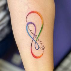 a tattoo on the leg of a woman with an infinite sign in rainbows and blue