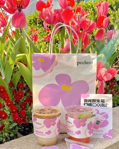 a pink flowered bag with two cups of coffee next to it