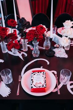 the table is set with red and white flowers, silverware, and candy bar