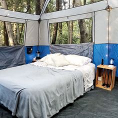 a bed sitting inside of a tent next to trees