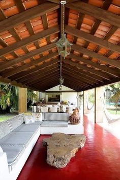 an outdoor living area with couches, tables and hammock hanging from the ceiling