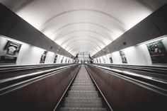 an empty subway station with escalators and people