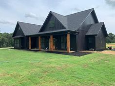 a large black house sitting on top of a lush green field