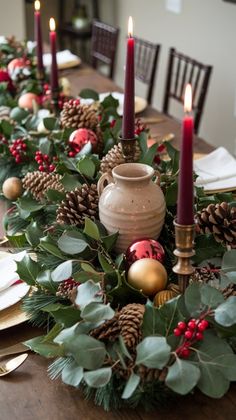 the table is set for christmas with candles and greenery