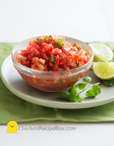 a bowl of salsa with limes and cilantro on the side