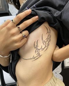 a woman's stomach with a tattoo on the side and her hand resting on it