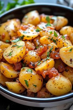 a bowl filled with potatoes covered in seasoning and garnished with parsley