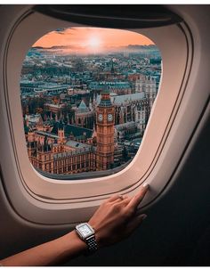 a person's hand on the window of an airplane looking out at london and big ben