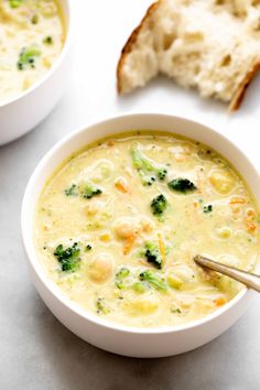 two bowls of soup with broccoli and cheese on the side, next to some slices of bread