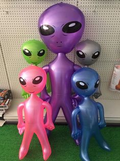 three inflatable alien figures are standing next to each other on the floor at a store