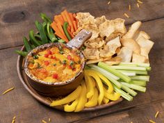 a bowl filled with dip surrounded by veggies and chips