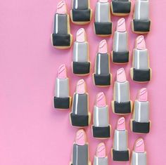 decorated cookies arranged in the shape of lipsticks on a pink and gray background with black accents