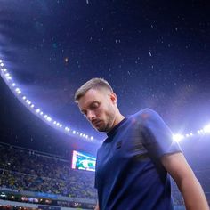 a man standing in the middle of a stadium at night with his hands on his hips