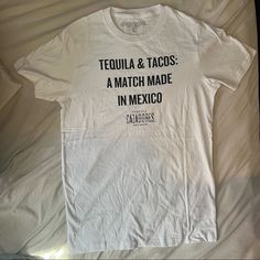 New “Tequila And Tacos - A Match Made In Mexico” White Tee This Is Official Cazadores Tequila Merch. White T-Shirt With Black Lettering On Front Reading “Tequila And Tacos - A Match Made In Mexico” . Short Sleeves, Adult Unisex Fit. Sizes Small Medium And Large. I Have Womens Fitted Sizes Too. Tags Alcohol Merchandise Bar Men Women Unisex, Top Shirt, Tee, Casual Logo, Branded White Graphic Print Tops For Cinco De Mayo, White Letter Print Tops For Cinco De Mayo, White Crew Neck Shirt For Cinco De Mayo, Casual White Top For Cinco De Mayo, Alcohol Merchandise, Casual Logo, Match Making, White Tee, White T Shirt