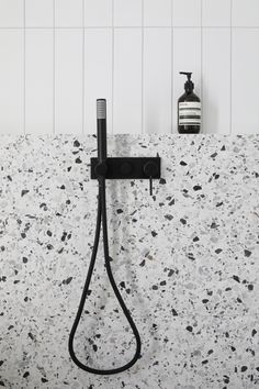 a black shower head in a white tiled bathroom