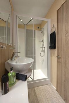 a white sink sitting next to a shower in a bathroom on top of a hard wood floor