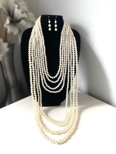 "Layered long white faux pearl necklace set for women Don't miss this opportunity to own this beautiful pearl necklace. This classic necklace is a timeless treasure and add a gorgeous glow to any outfit. Eight layers of pearls make this necklace truly statement piece! This multi strand necklace is made from high quality acrylic pearls, silver lobster clasp and adjustable chain. Measurement: First strands  25\"long+ext.(63 cm) Last strands 48\" long (122 cm) **I will pair this necklace with earri Pearl White Multi-strand Pearl Necklace, Elegant Multi-strand Pearl Layered Necklace, Long Pearl Beaded Necklaces With Pearl Chain, White Pearl Pendant Backdrop Necklace, White Elegant Multi-strand Layered Necklace, Elegant White Beaded Necklace With Pearl Chain, Elegant White Multi-strand Layered Necklace, Elegant White Multi-strand Long Necklace, Elegant White Pearl Chain Backdrop Necklace