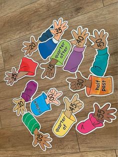 several colorful stickers with hands and numbers in them on a wooden floor next to a pair of scissors