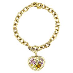 This charming and elegant bracelet, featuring a single heart charm, is exquisitely crafted in 18 karat yellow gold. The removable charm is adorned with a dazzling array of multi-colored gemstones, creating a vibrant and captivating centerpiece. Surrounding the heart is a delicate halo of diamonds, adding an extra layer of sparkle and sophistication. The luxurious yellow gold setting beautifully complements the colorful gemstones and diamonds, making this piece a stunning accessory for any occasion. Combining playful design with refined elegance, this charm bracelet is a delightful addition to any fine jewelry collection. This piece is in very good estate condition and has been professionally cleaned and polished. It comes with an appraisal card, verifying its authenticity and current appra Gold Diamond Heart Charm Bracelet, Luxury Yellow Gold Diamond Heart Bracelet, Luxury Yellow Gold Heart Cut Bracelet, Luxury Yellow Gold Heart Bracelet, Luxury Yellow Gold Heart Bracelet With Charm, Luxury Yellow Gold Heart Bracelet With Heart Charm, Luxury Yellow Gold Heart Charm Bracelet, Luxury Yellow Gold Bracelet With Heart Charm, Luxury Yellow Gold Heart-shaped Bracelet